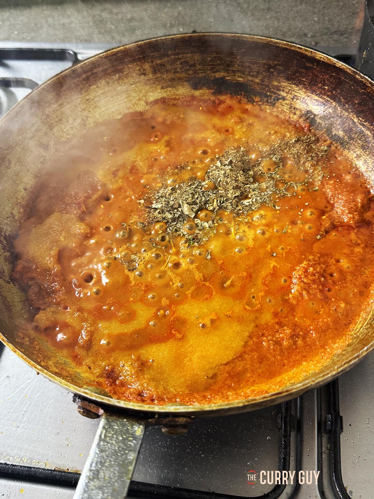 Adding the kasoori methi and more base to the pan.