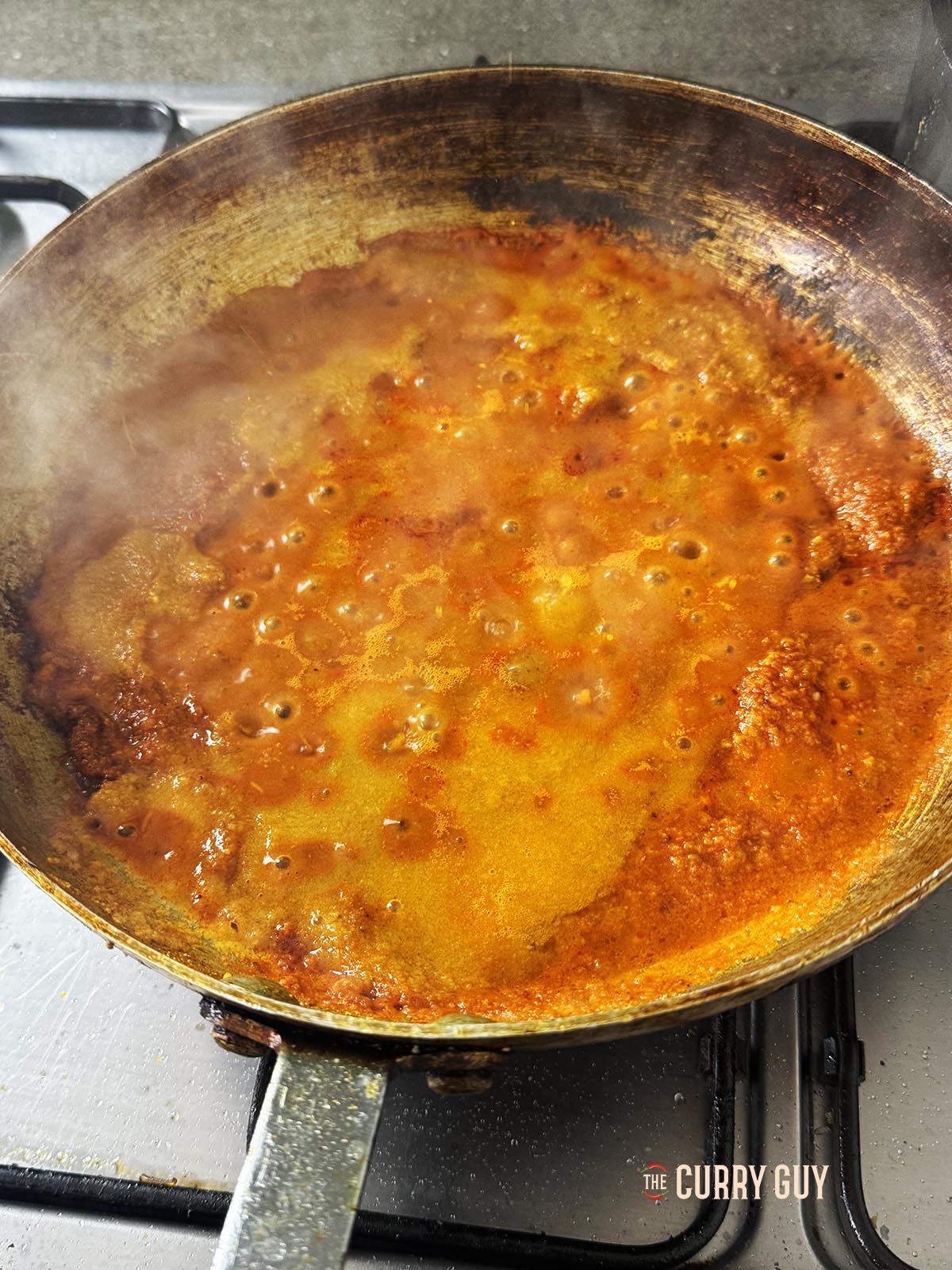 Adding more base sauce to the pan.