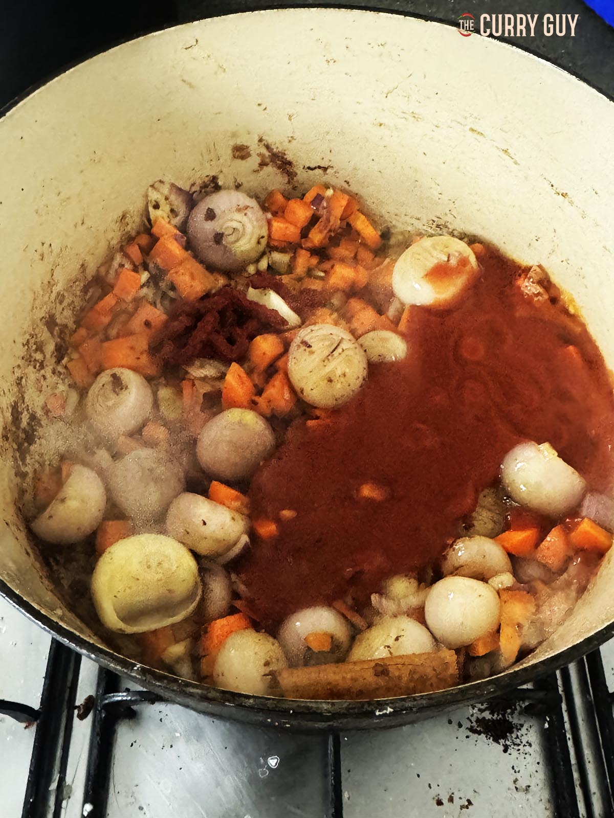 Adding the wine and beef stock and bringing to a simmer in the pot.