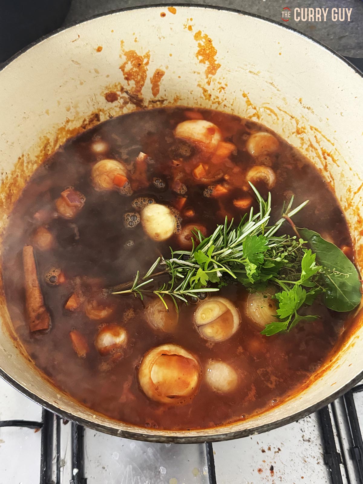 Adding the red wine, beef stock and bouquet garni to the pot.