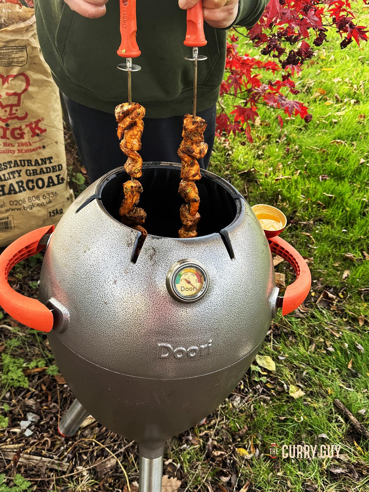 Turing the skewers in the tandoor so that they cook evenly.