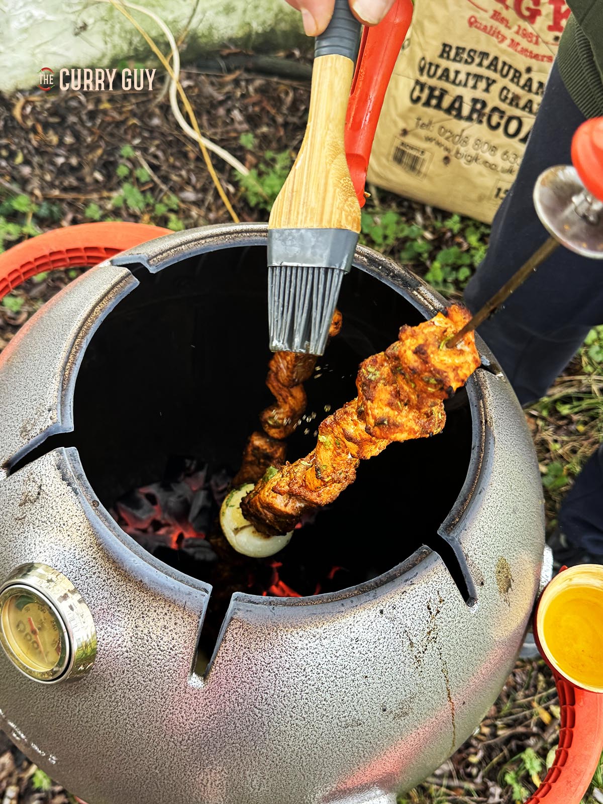 Basting the salmon tikka with melted ghee.