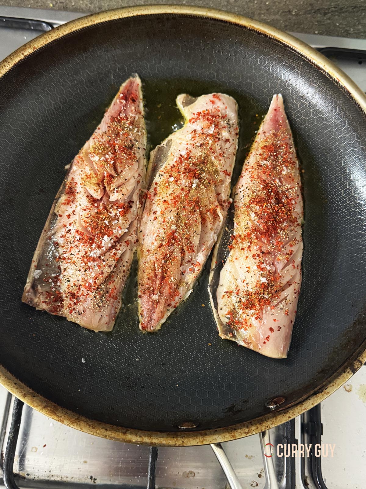 Frying the fish fillets coated with the spices in olive oil in a frying pan.