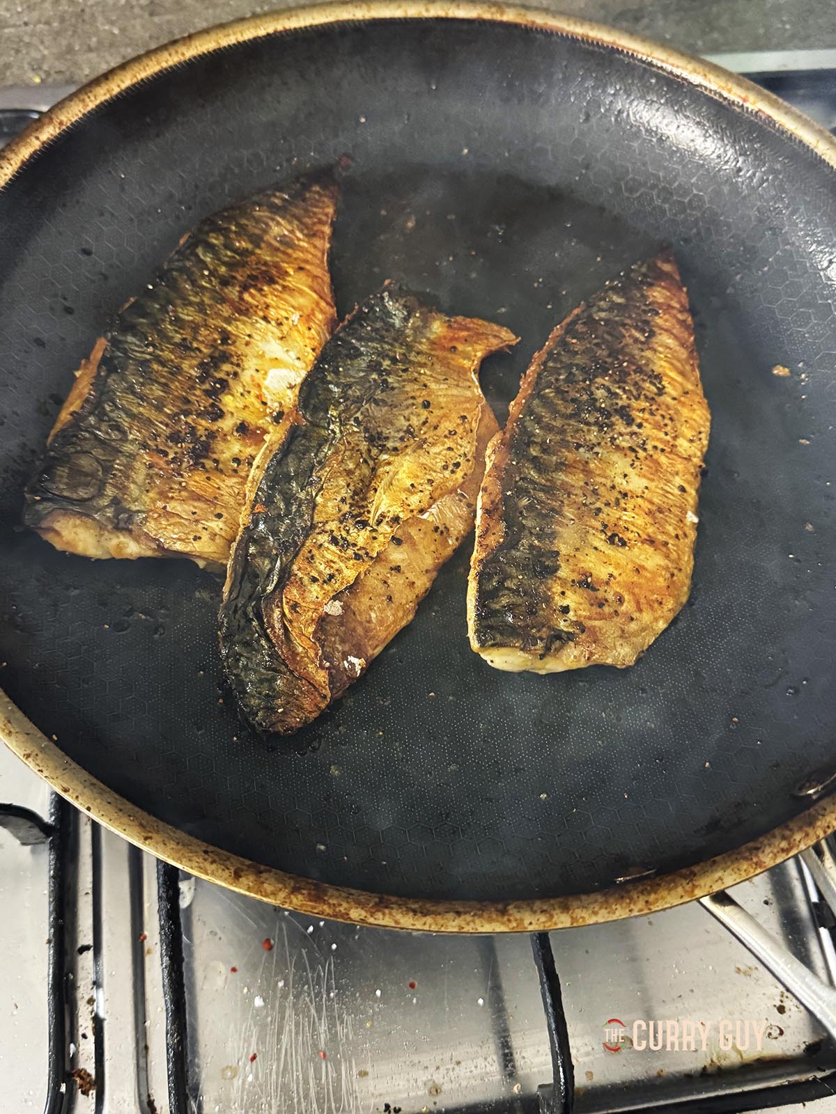Frying the fish fillets skin side up in the pan.