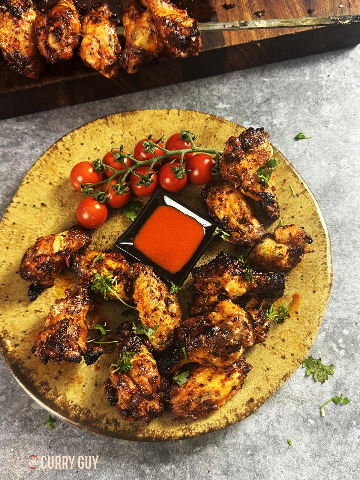 Serving the Turkish chicken wings on a plate with hot sauce for dipping.