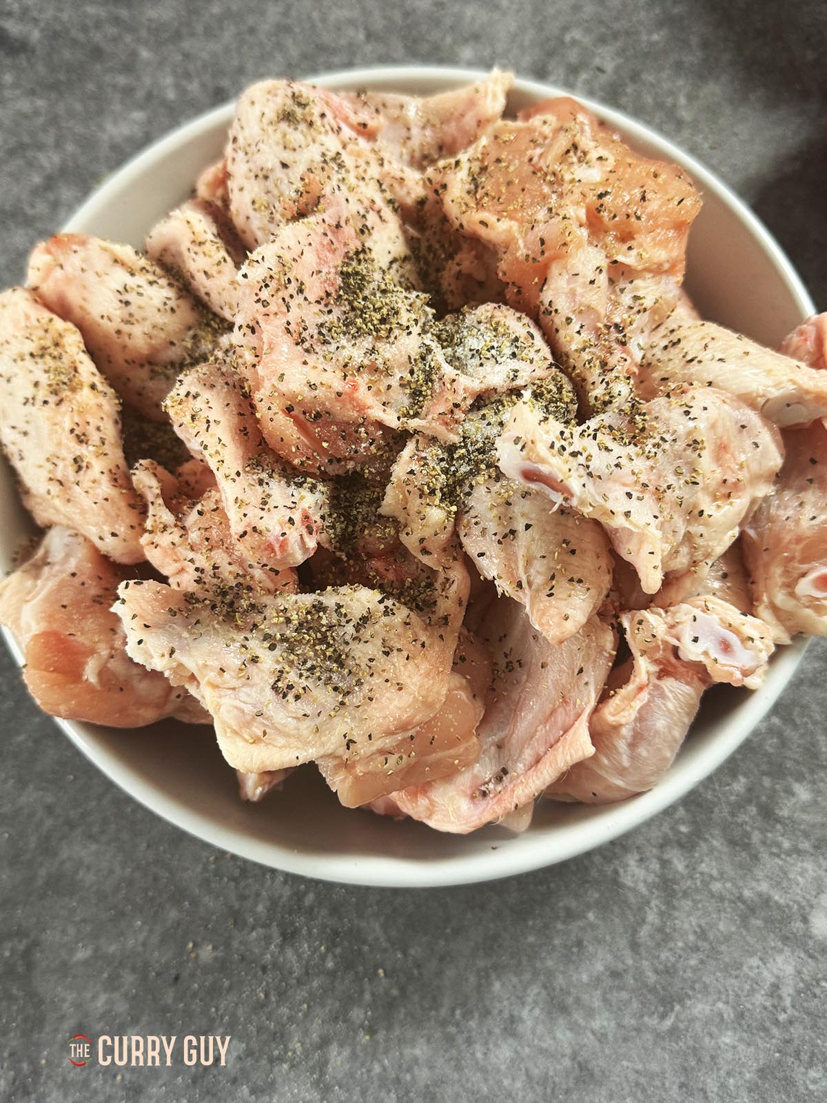 The chicken wings seasoned with salt and pepper in a bowl.