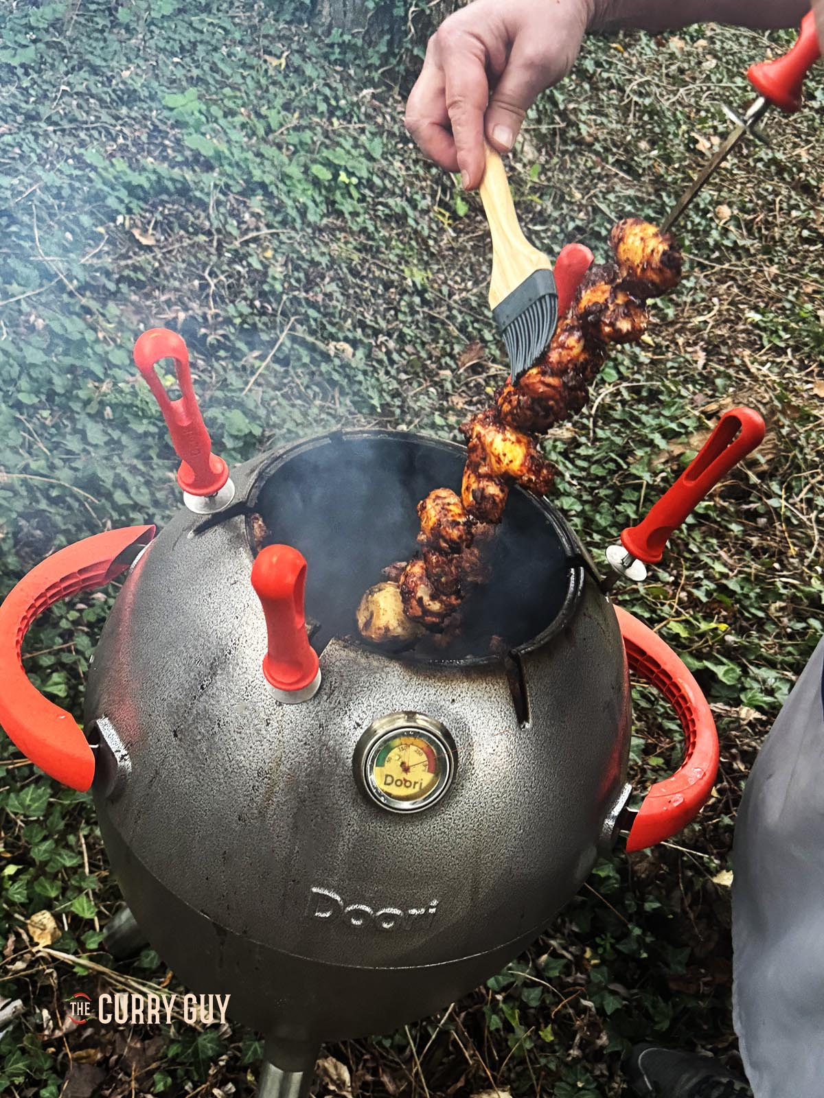 Basting the chicken wing skewers with ghee.