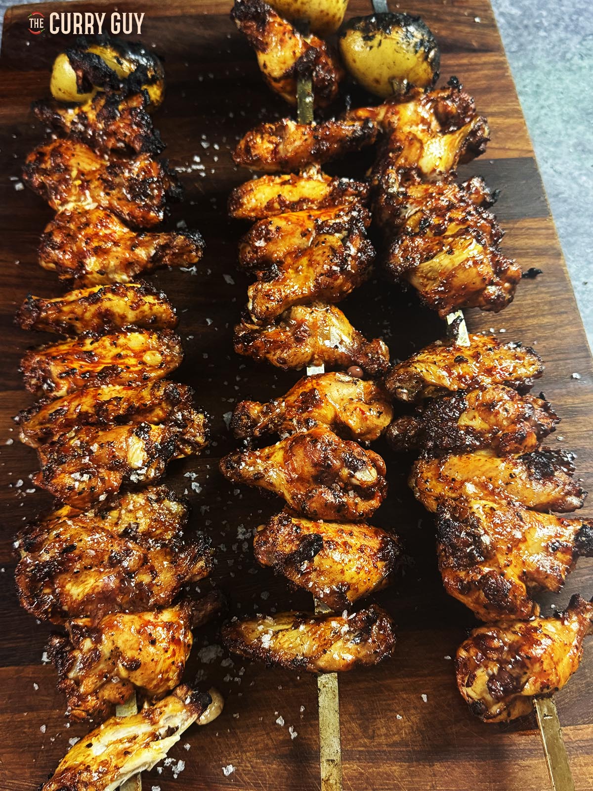 The cooked chicken wings on a cutting board on skewers.