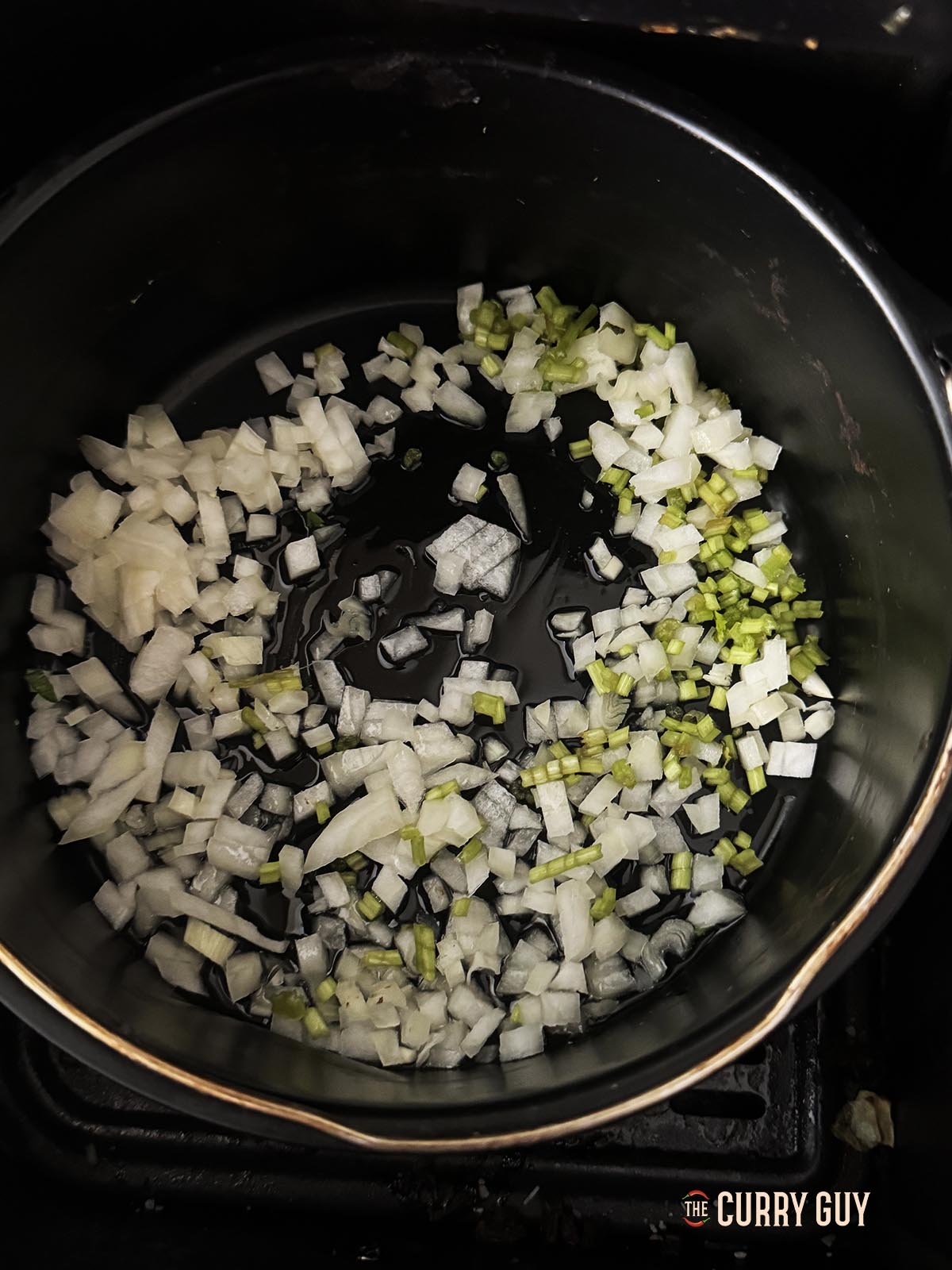 The onions and coriander stems cooking in the air fryer in a cake tin. 