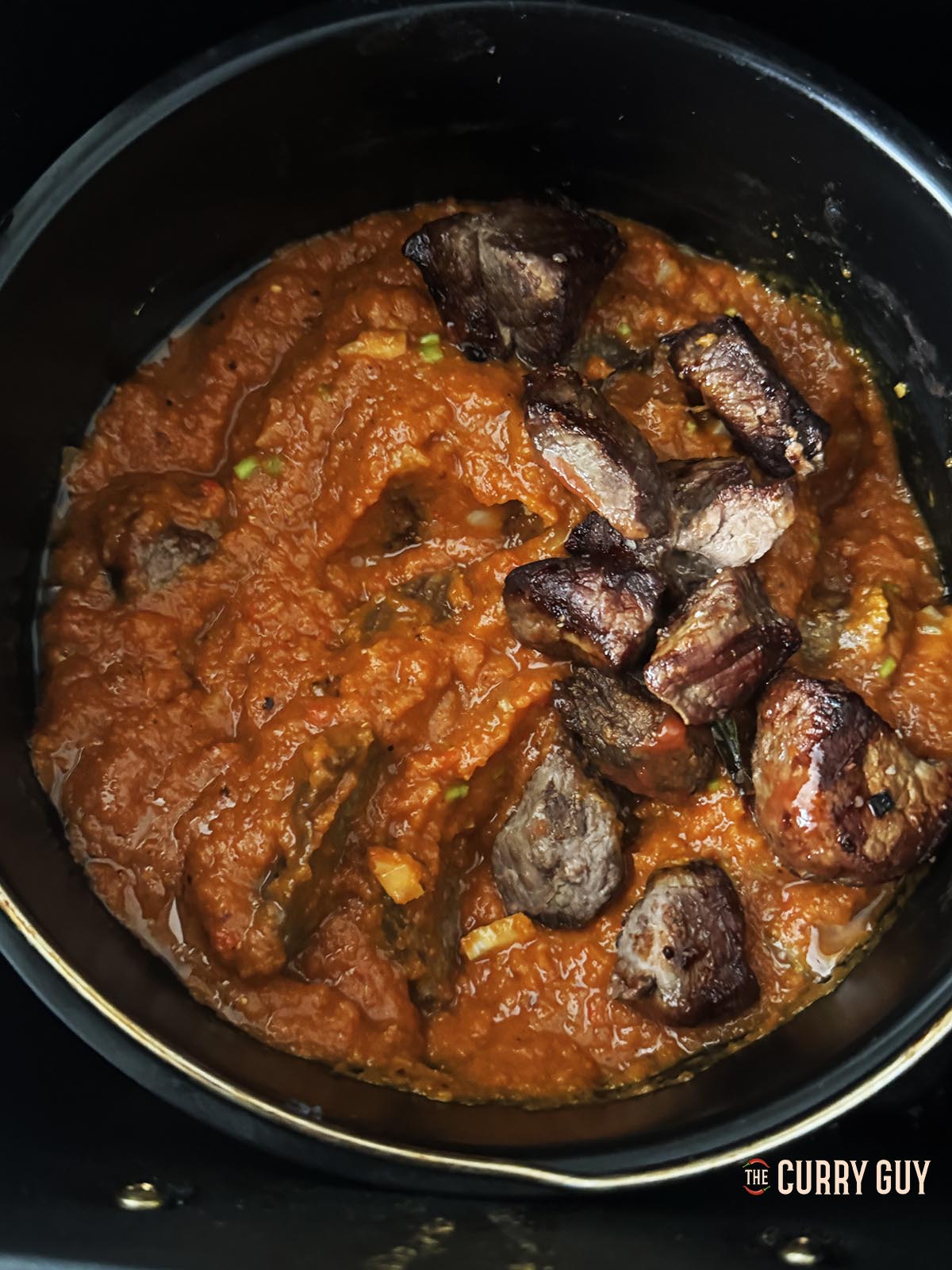Returning the blended sauce to the air fryer along with the cooked meat.