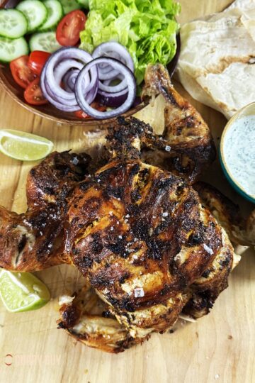 Slow cooker tandoori chicken on a serving platter with side dishes.