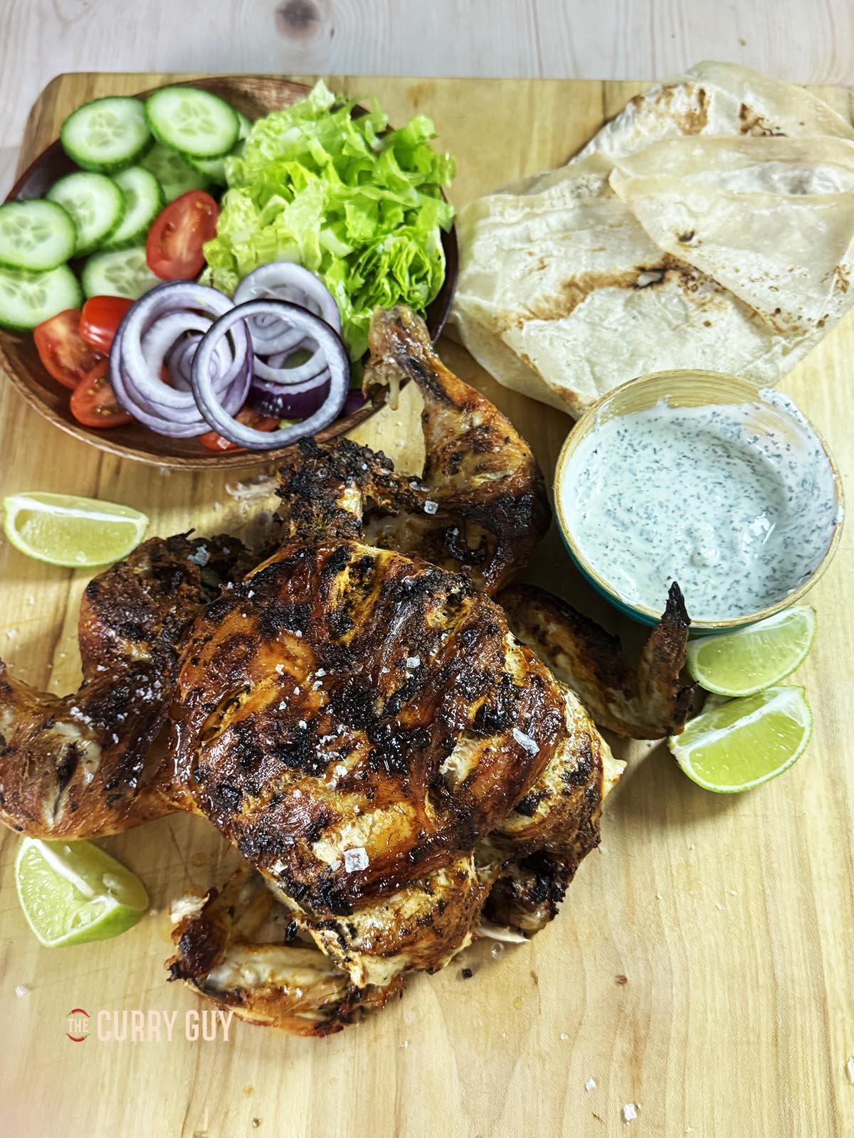 Slow cooker tandoori chicken on a serving platter with side dishes.