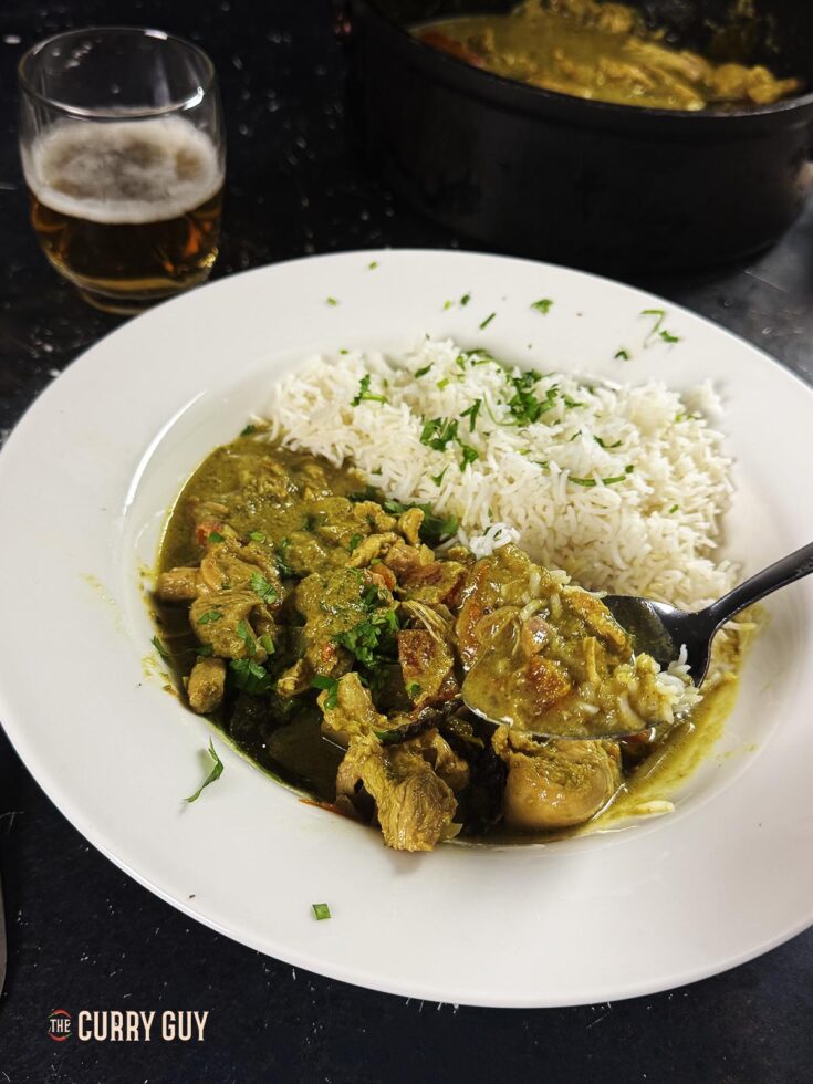 Slow cooker spicy chicken curry on a serving plate with a side of Basmati rice.