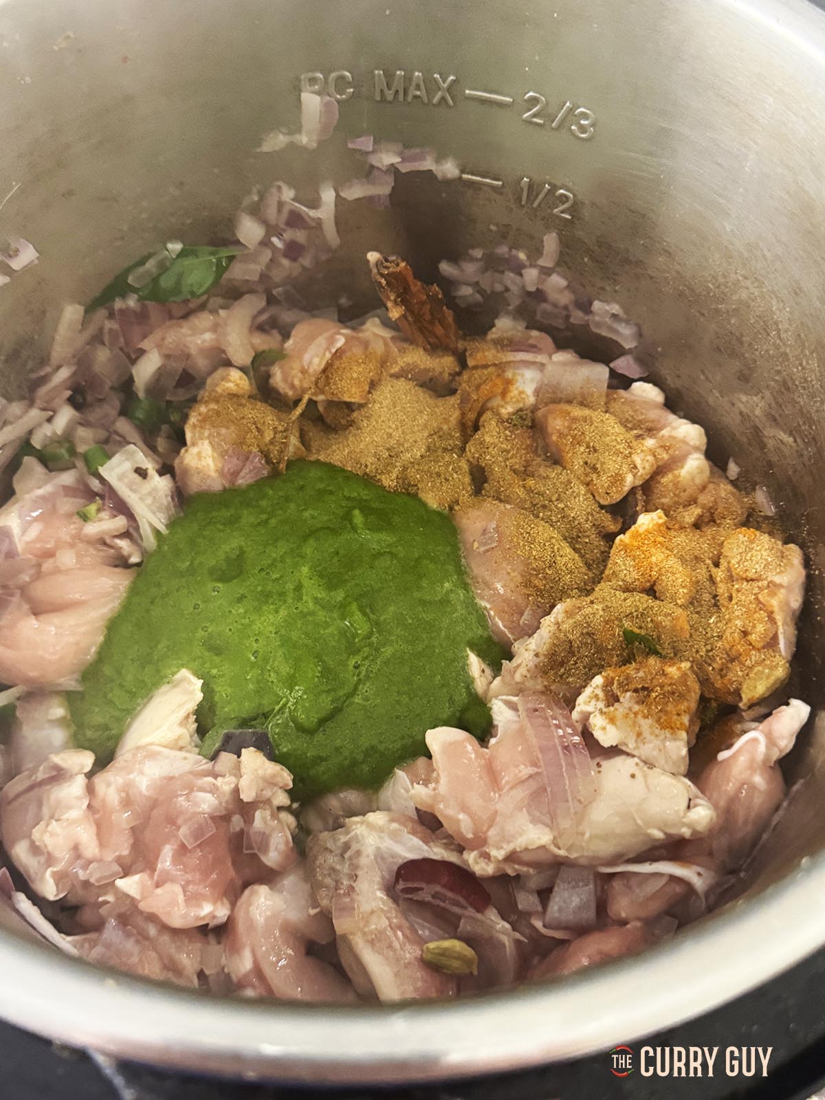 Adding the chicken, chilli paste and ground spices to the pan.