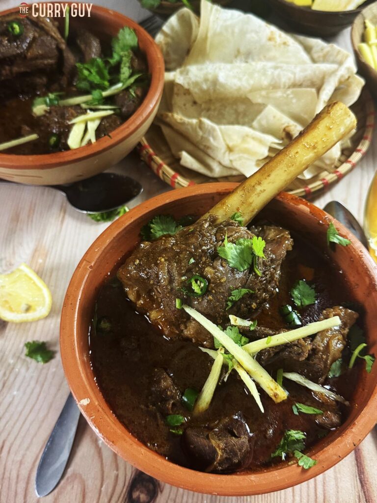 Slow cooker nihari in a serving bowl garnished with julienned ginger, chopped green chillies and chopped coriander (cilantro).
