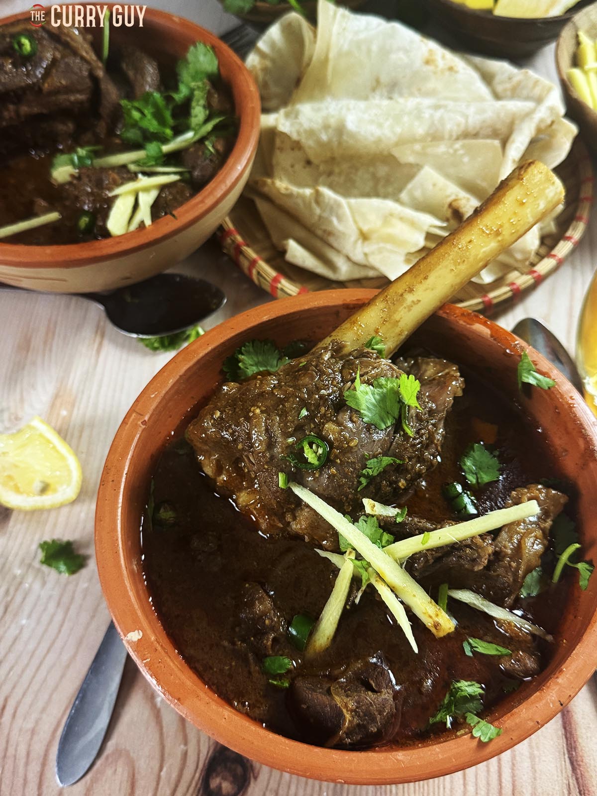 Slow cooker nihari in a serving bowl garnished with julienned ginger, chopped green chillies and chopped coriander (cilantro).