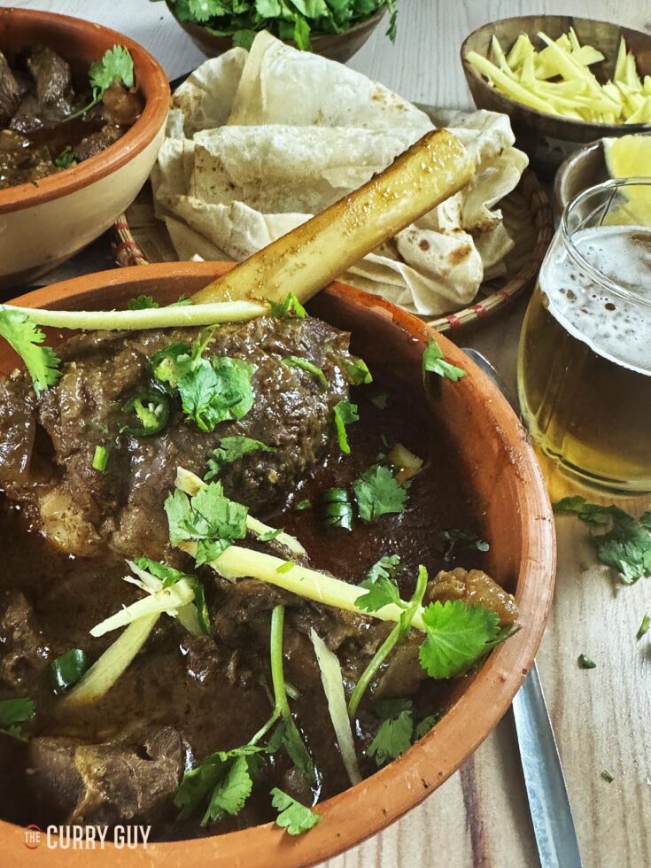 Slow cooker nihari in a serving bowl and garnished with ginger, coriander and green chillies.