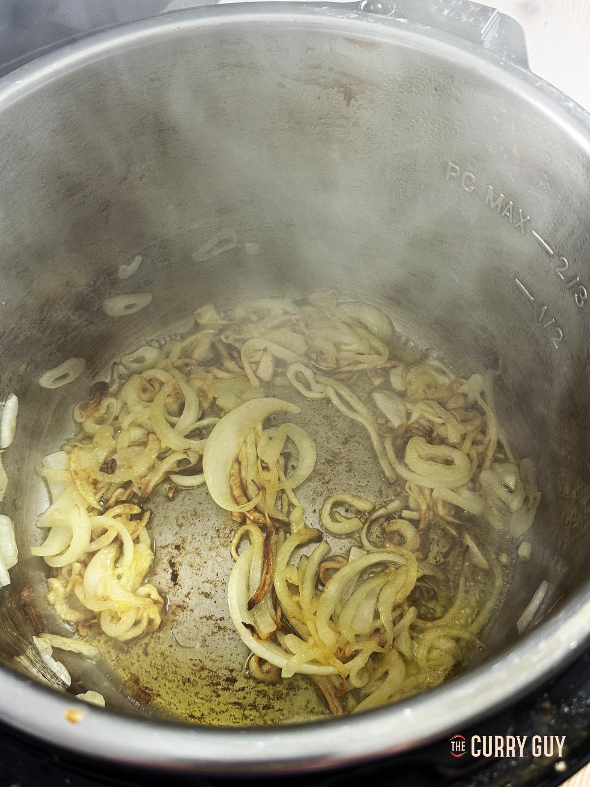 Frying the onions in the ghee until soft, translucent and lightly browned.