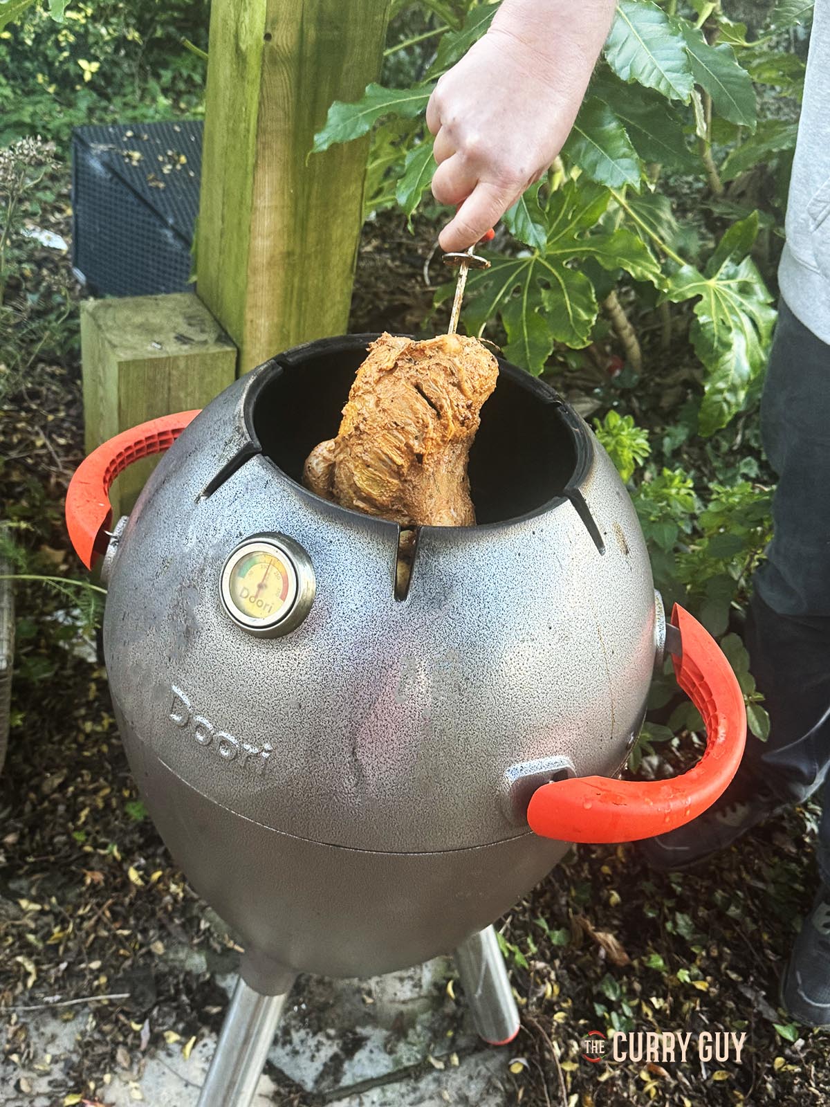 Placing the skewered pheasant in the tandoor oven.