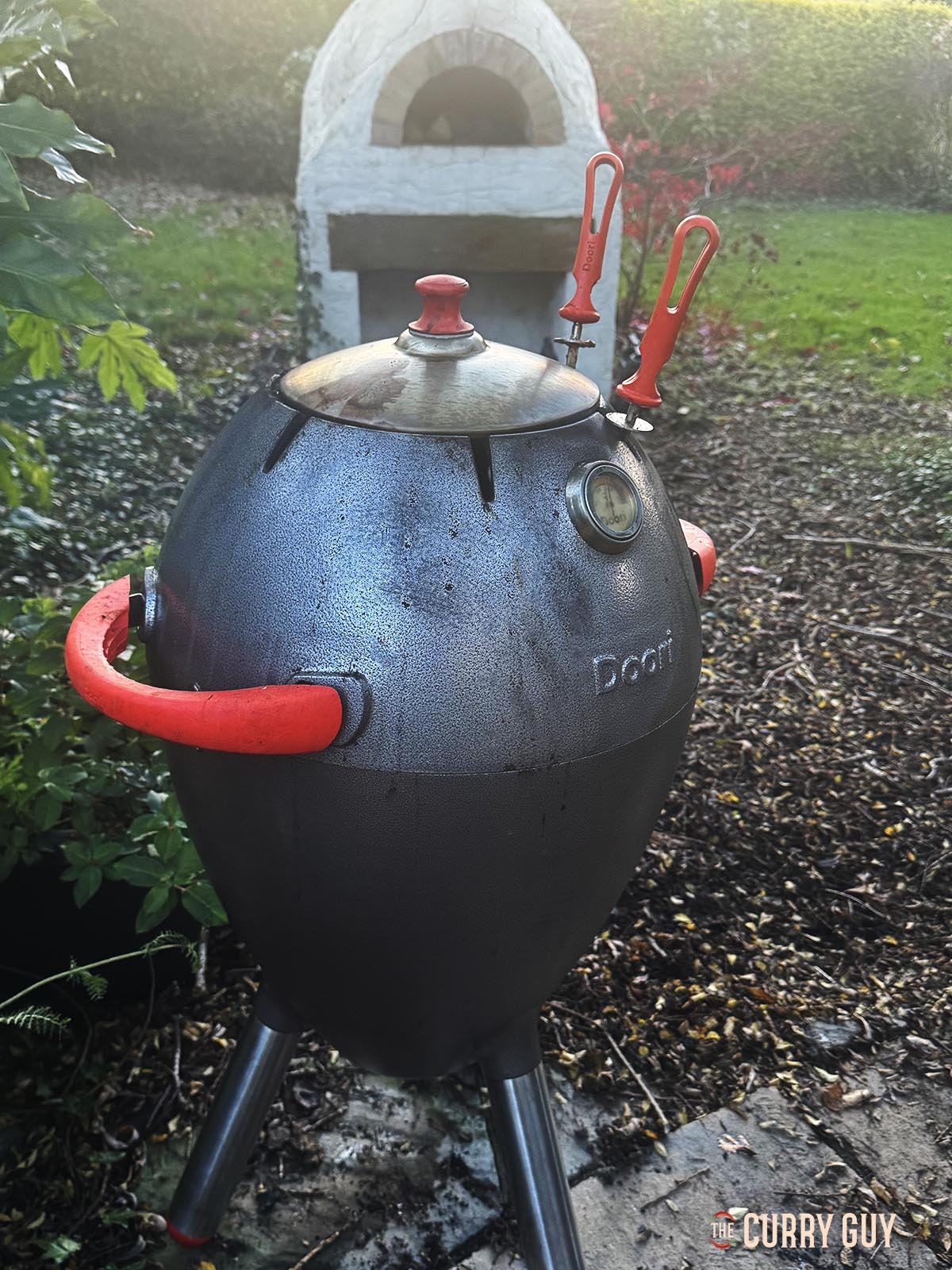 Cooking the pheasant with the lid closed on the tandoor to maintain the heat.