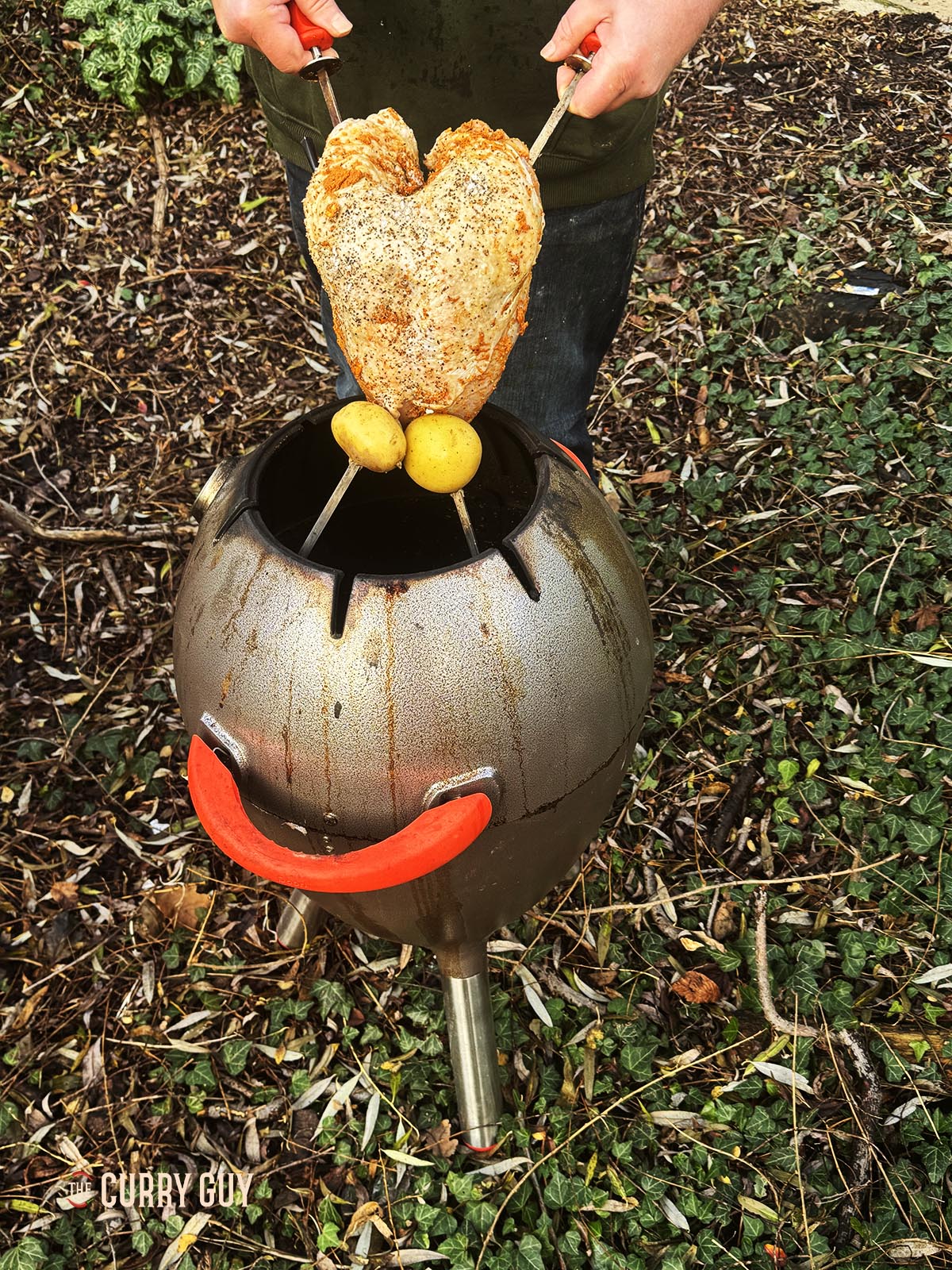 Lowering the turkey crown into the tandoor oven. 
