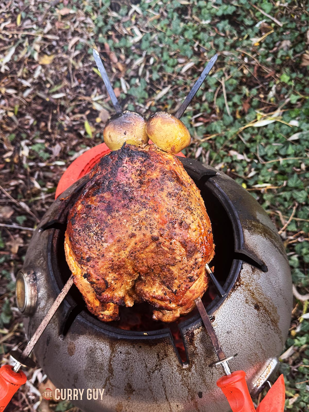 The turkey cooking and smoking on top of the tandoor.