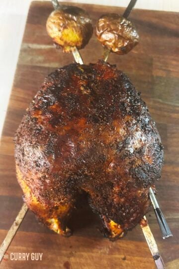 Skewered tandoori turkey crown on a cutting board, cooked to perfection.