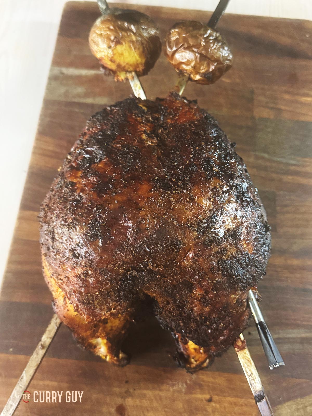 Skewered tandoori turkey crown on a cutting board, cooked to perfection.