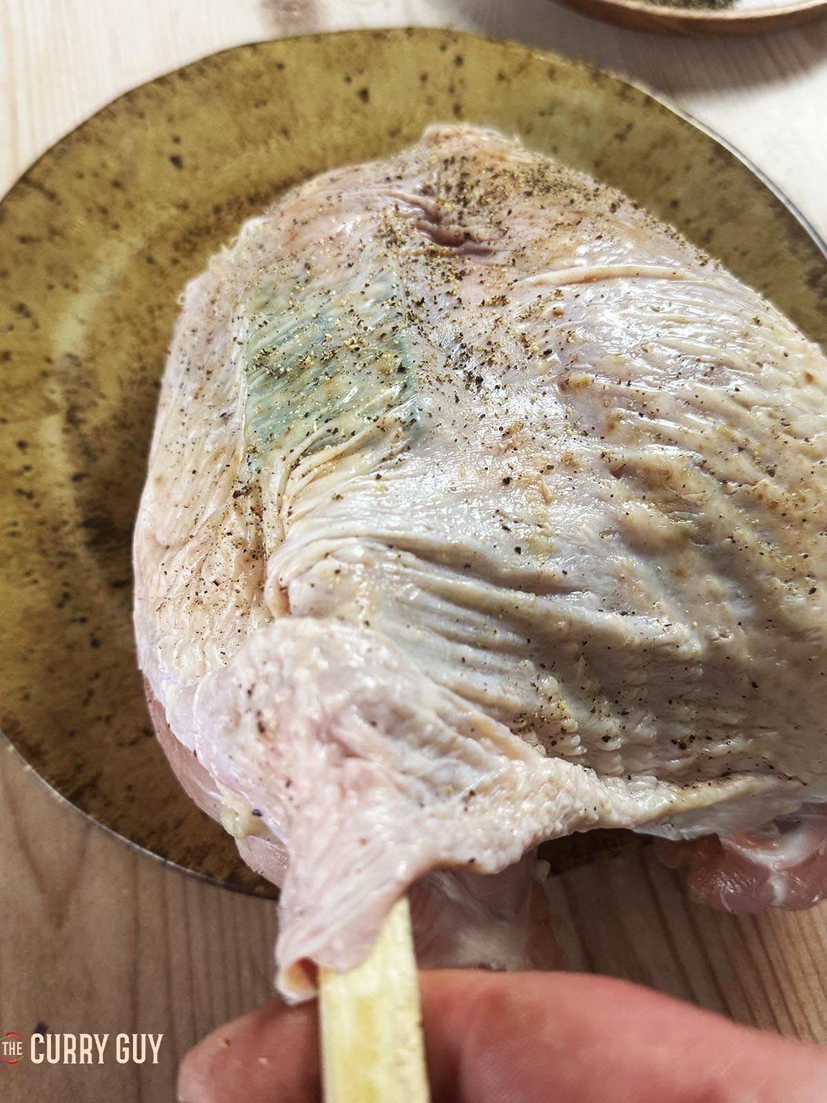 Using a rubber spatula to separate the skin from the meat of the turkey crown.