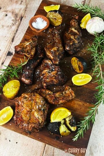 Grilled rabbit on a serving board with lemon wedges to squeeze over the top.