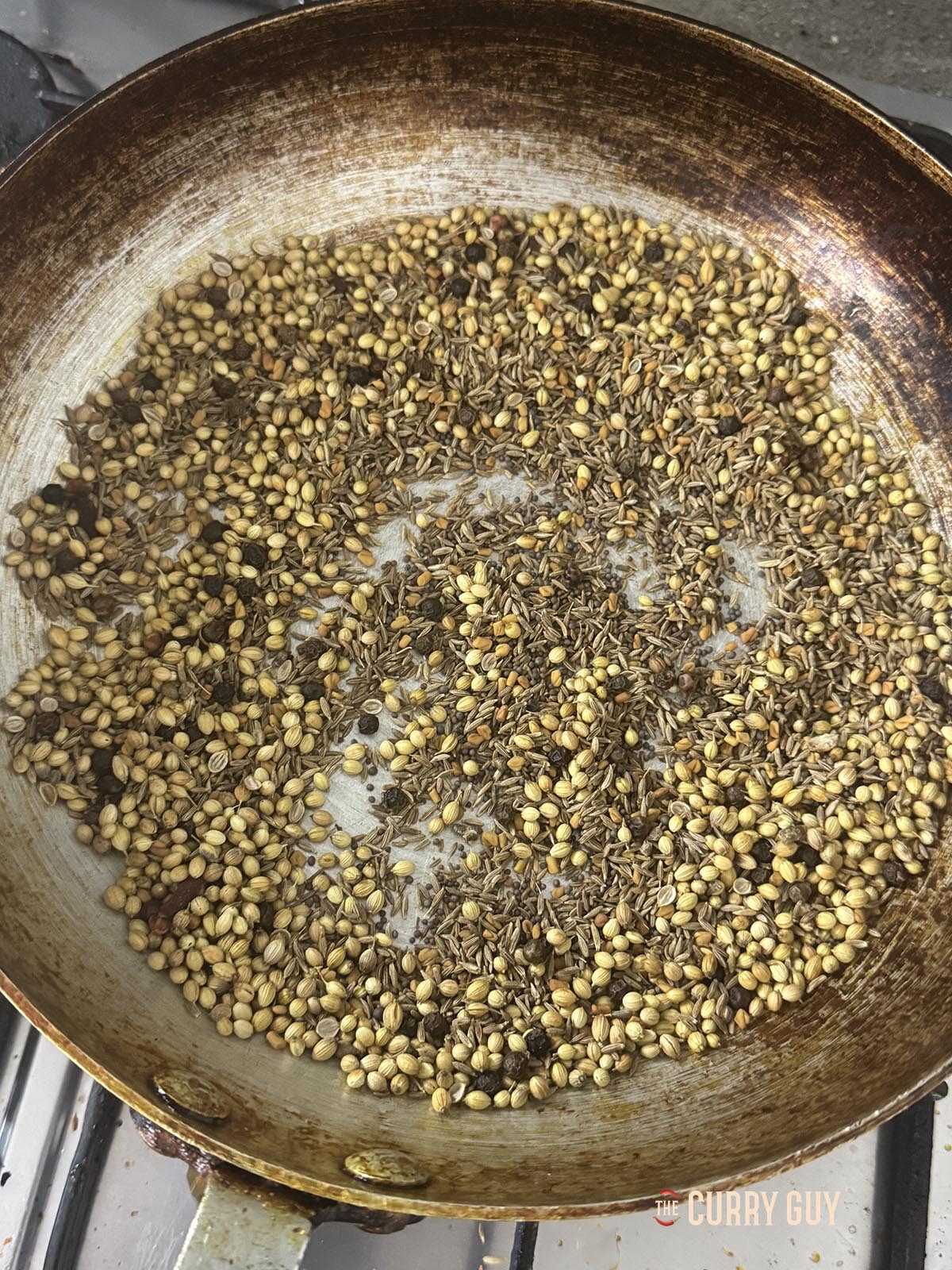 Roasting the whole spices in a frying pan.