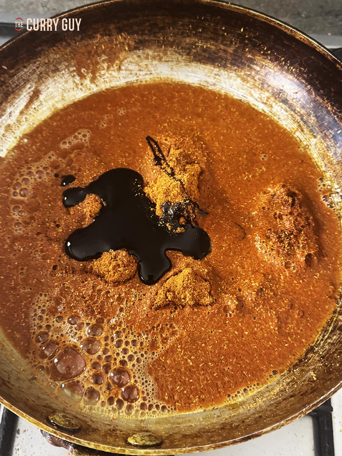Adding the curry powder to a pan with the water and tamarind concentrate. 