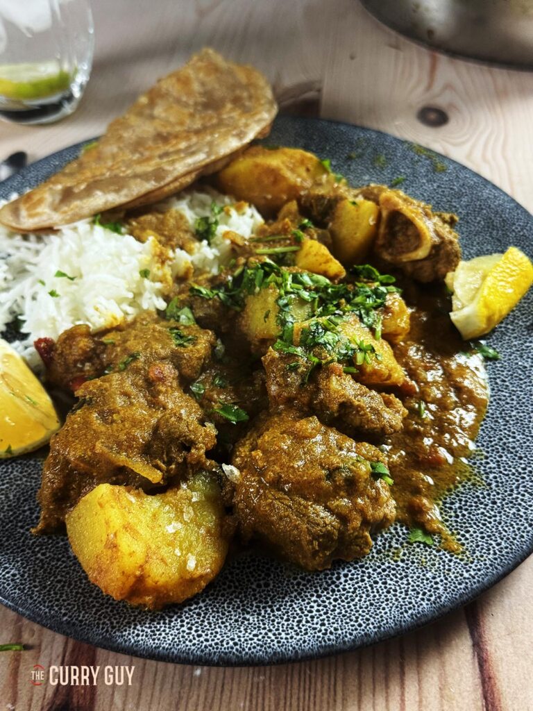 Slow cooker railway lamb curry on a serving plate with rice and chapati.