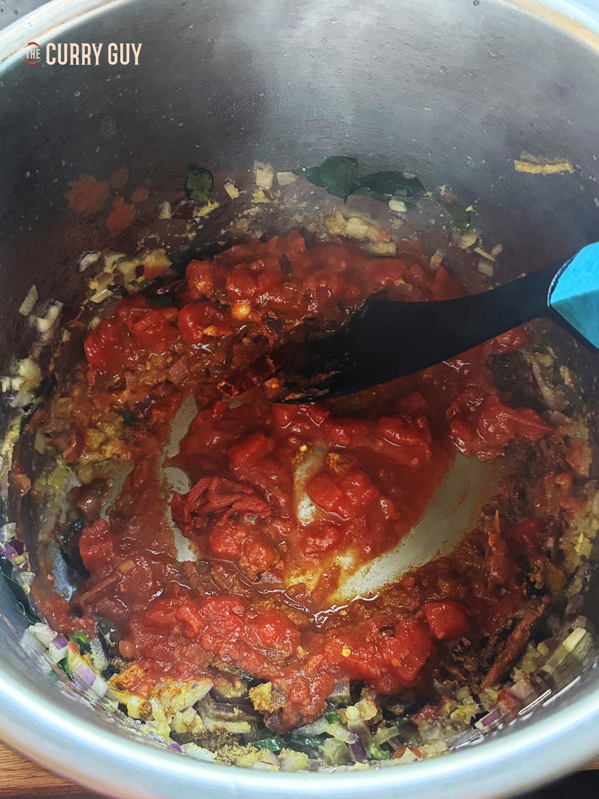 Adding the ground spices and chopped tomato to the pot. 