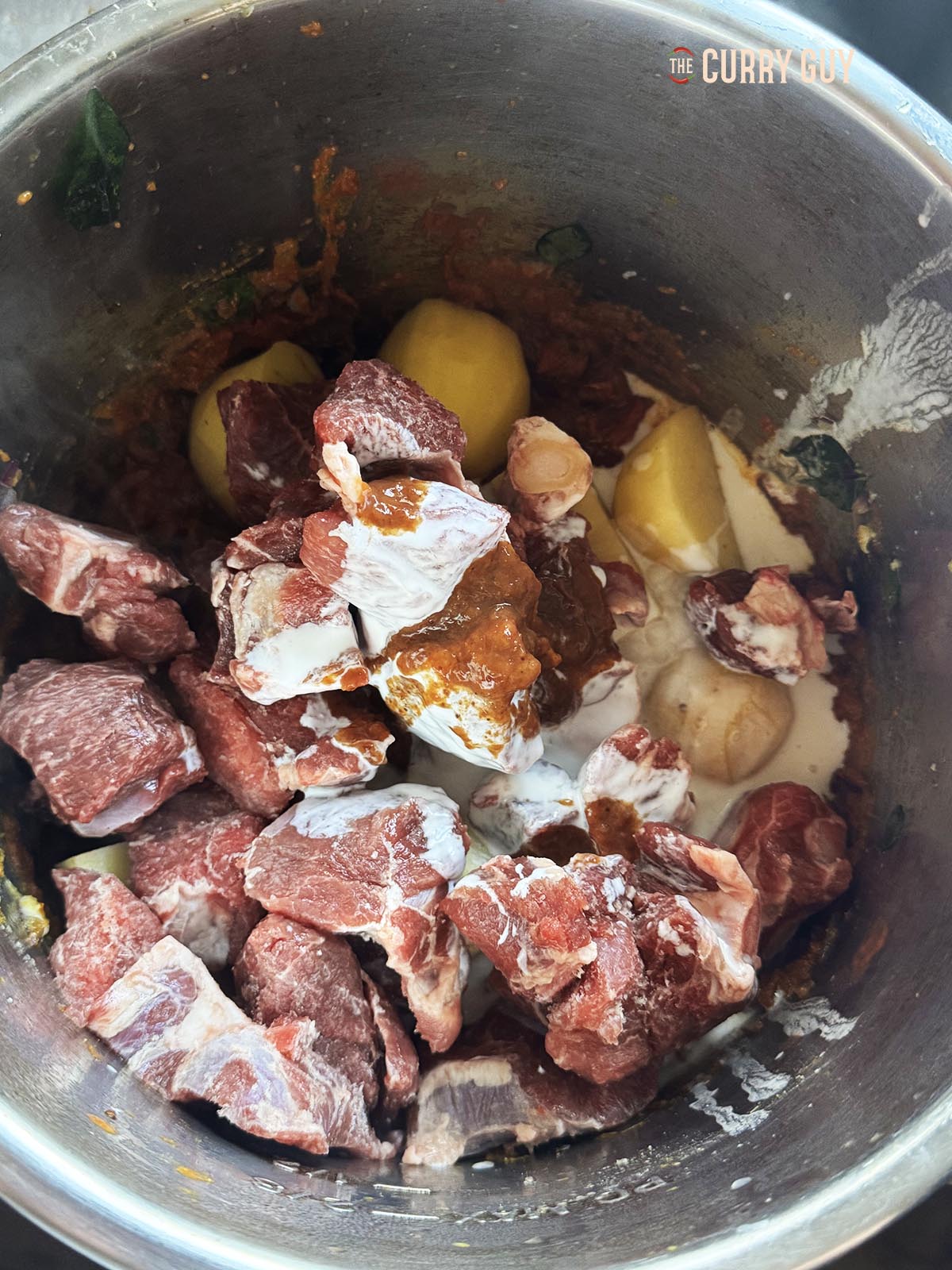 Stirring in the meat, potatoes, tamarind concentrate and coconut milk.