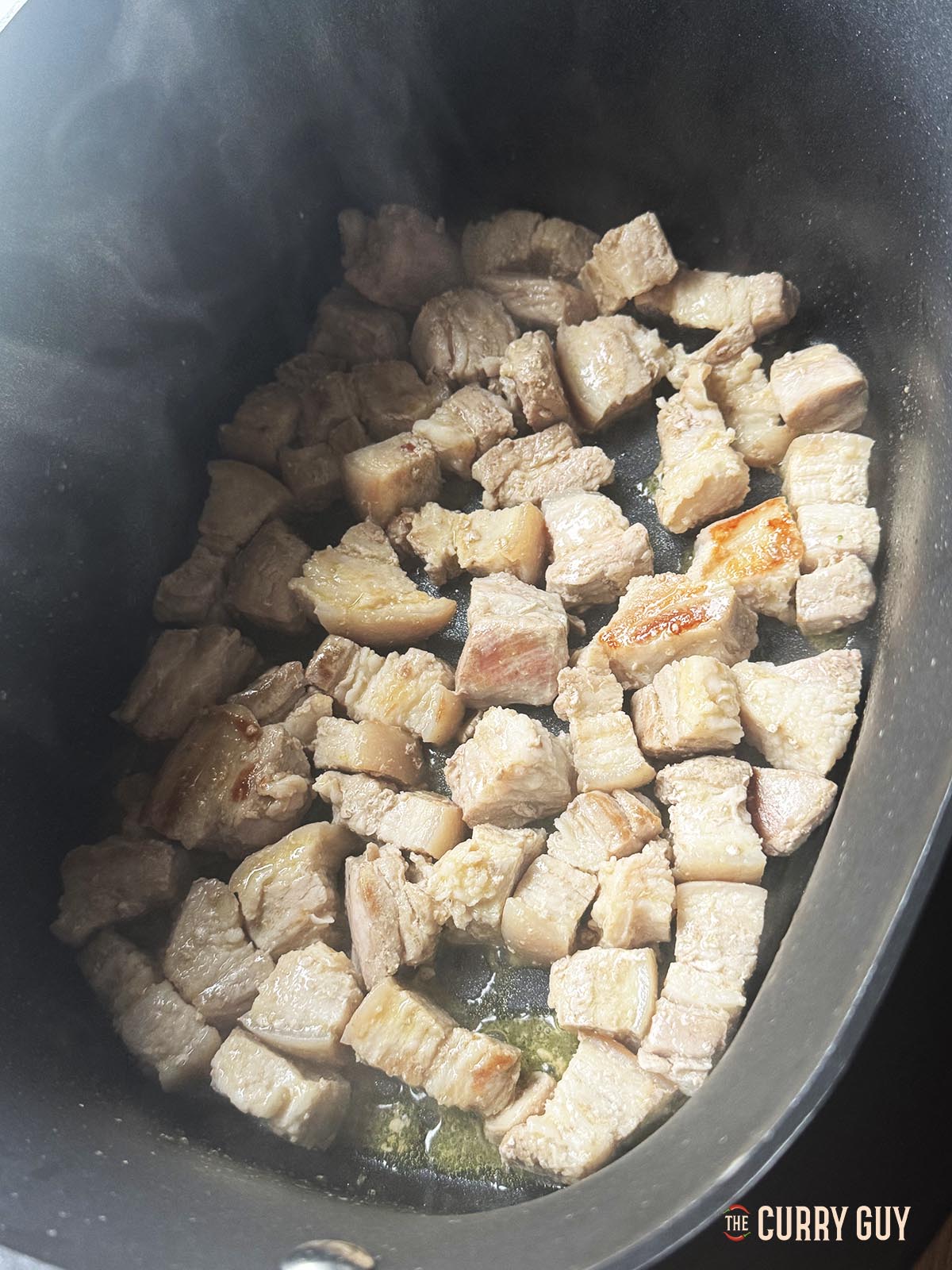 Frying the pork belly pieces to brown them.