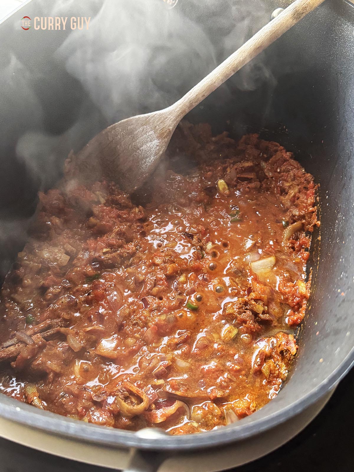 Adding the chopped tomatoes and water to the slow cooker.
