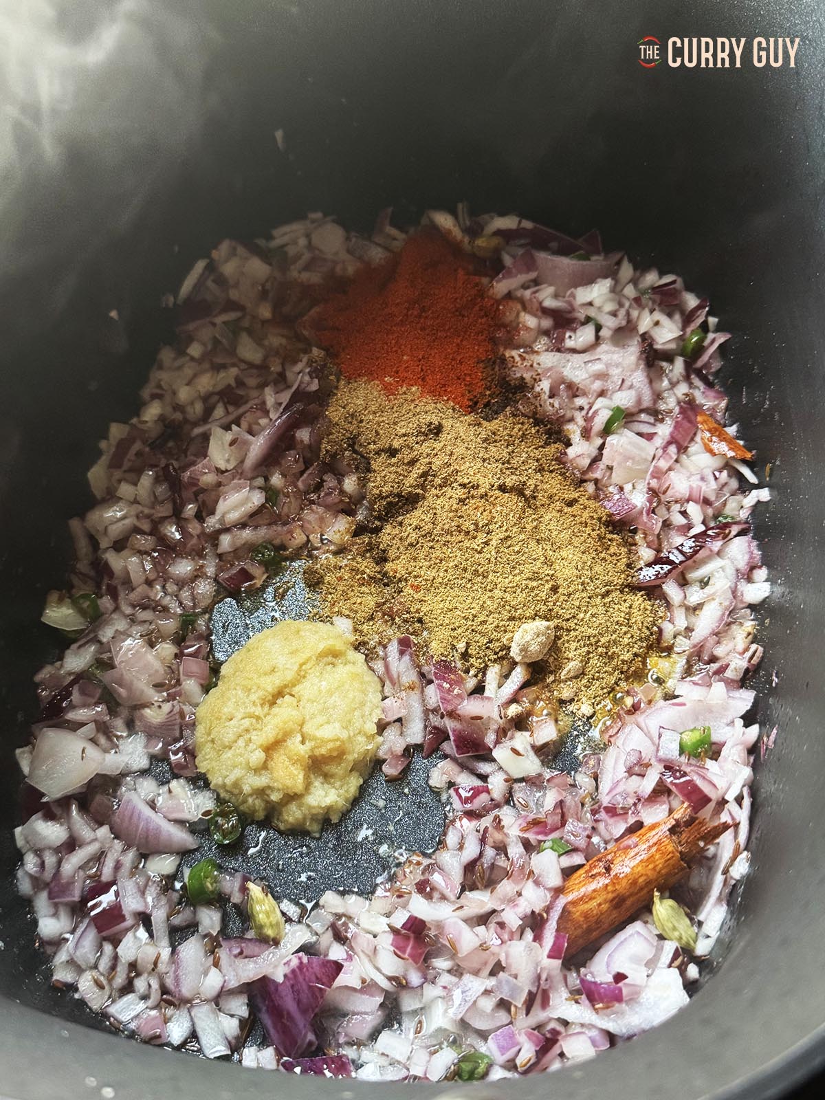 Adding the ground spices to the onion mixture in the slow cooker.