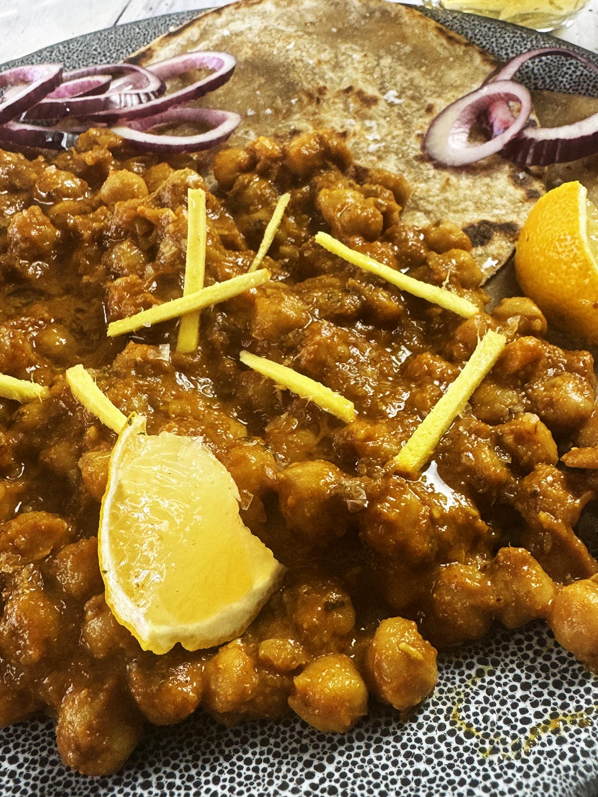 The slow cooker chickpea curry on a serving plate with parathas.