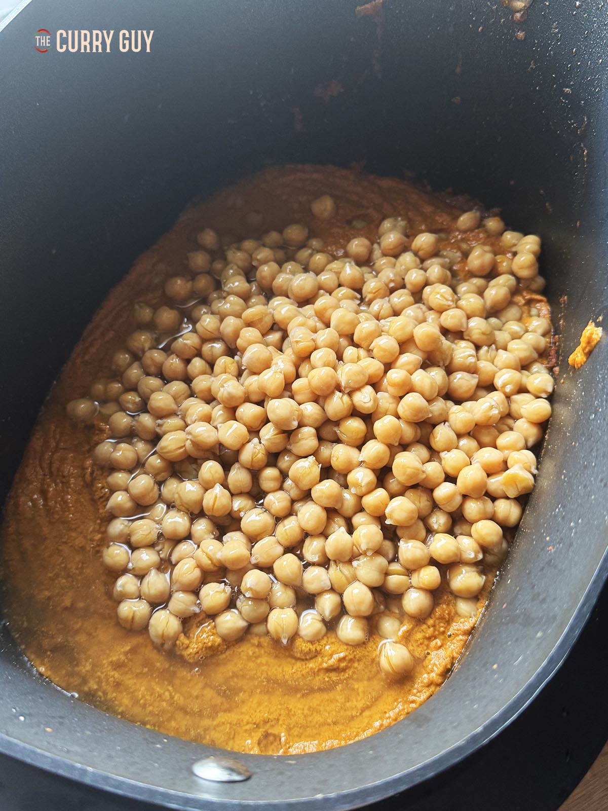 Adding the chickpeas to the blended sauce.