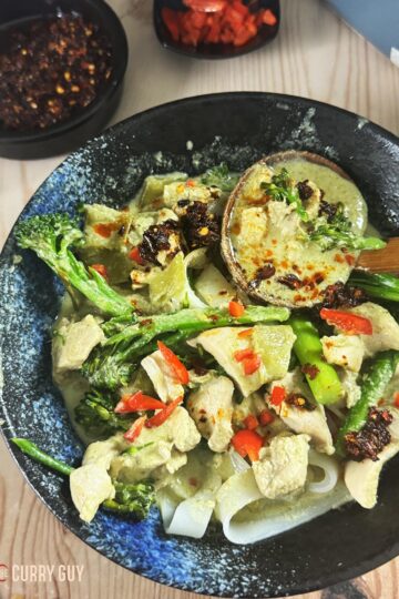 Slow cooker Thai green curry in a bowl with rice noodles.