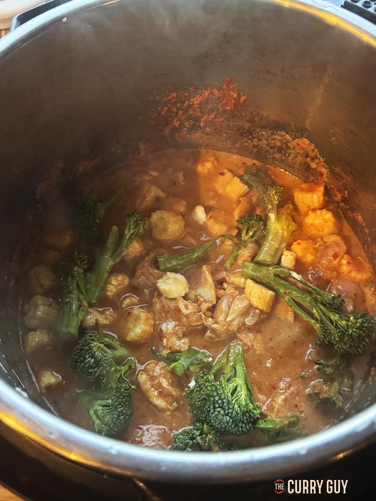 Adding vegetables to the sauce in the slow cooker.
