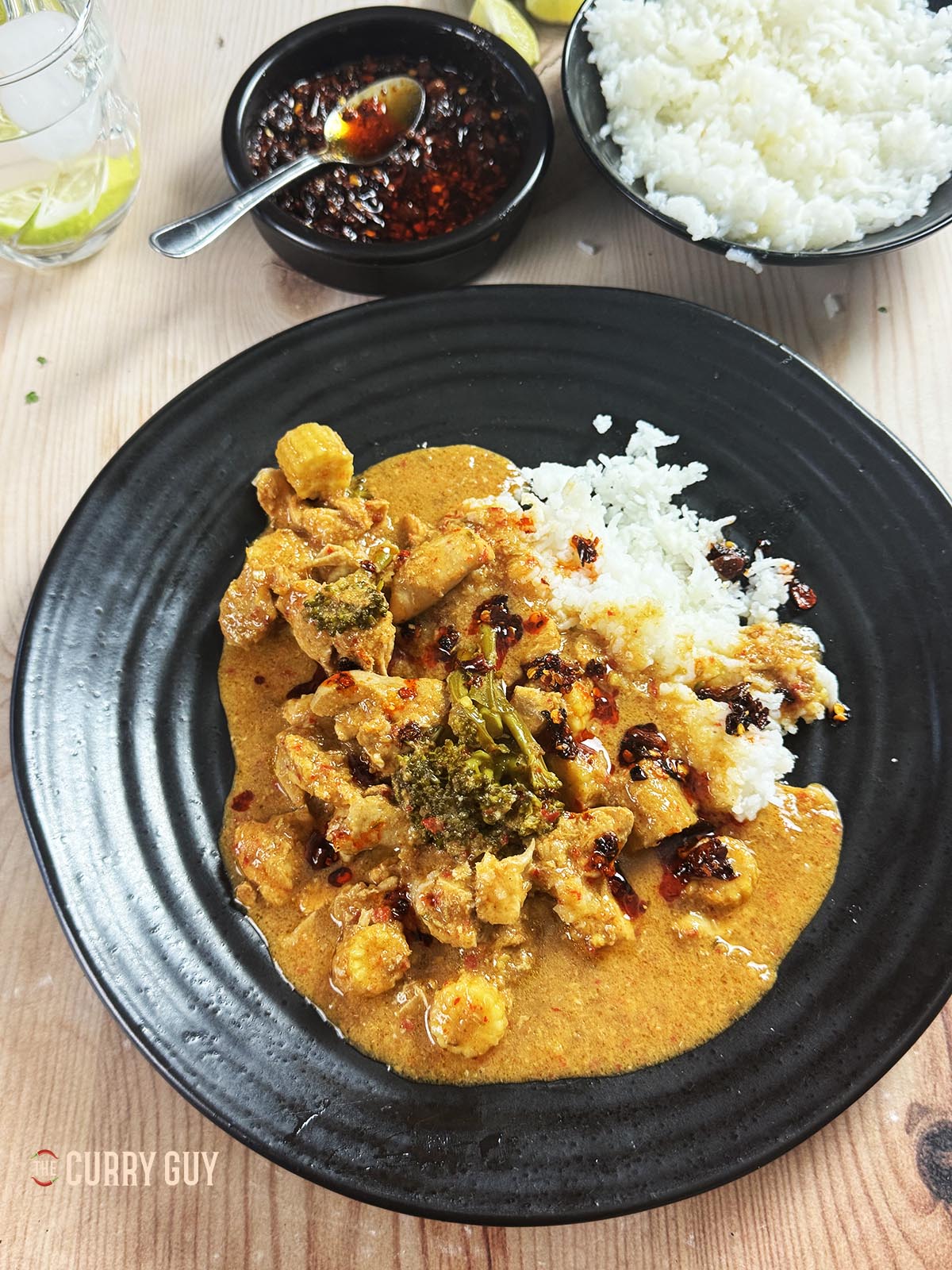Slow cooker red Thai curry on a serving plate with rice and crispy chilli oil. 
