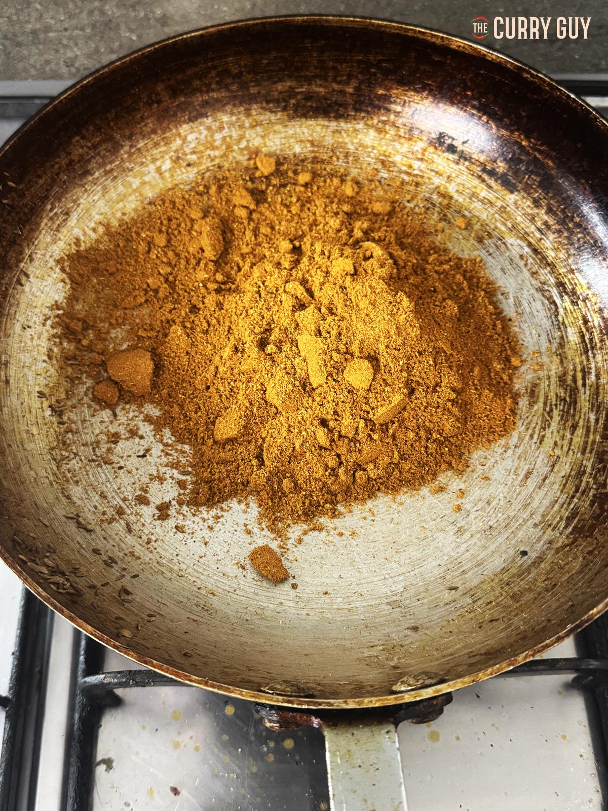 Pouring the ground spice powder into a pan.