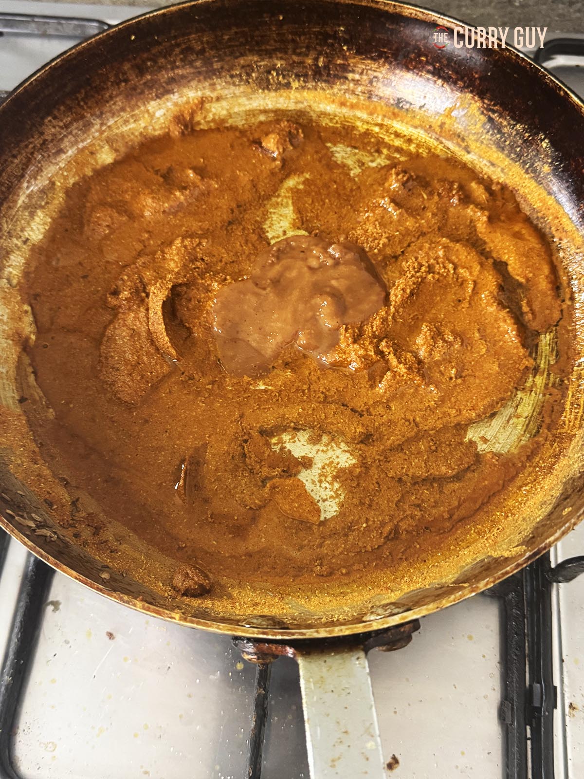 Adding water and tamarind concentrate to the spices to make a paste.