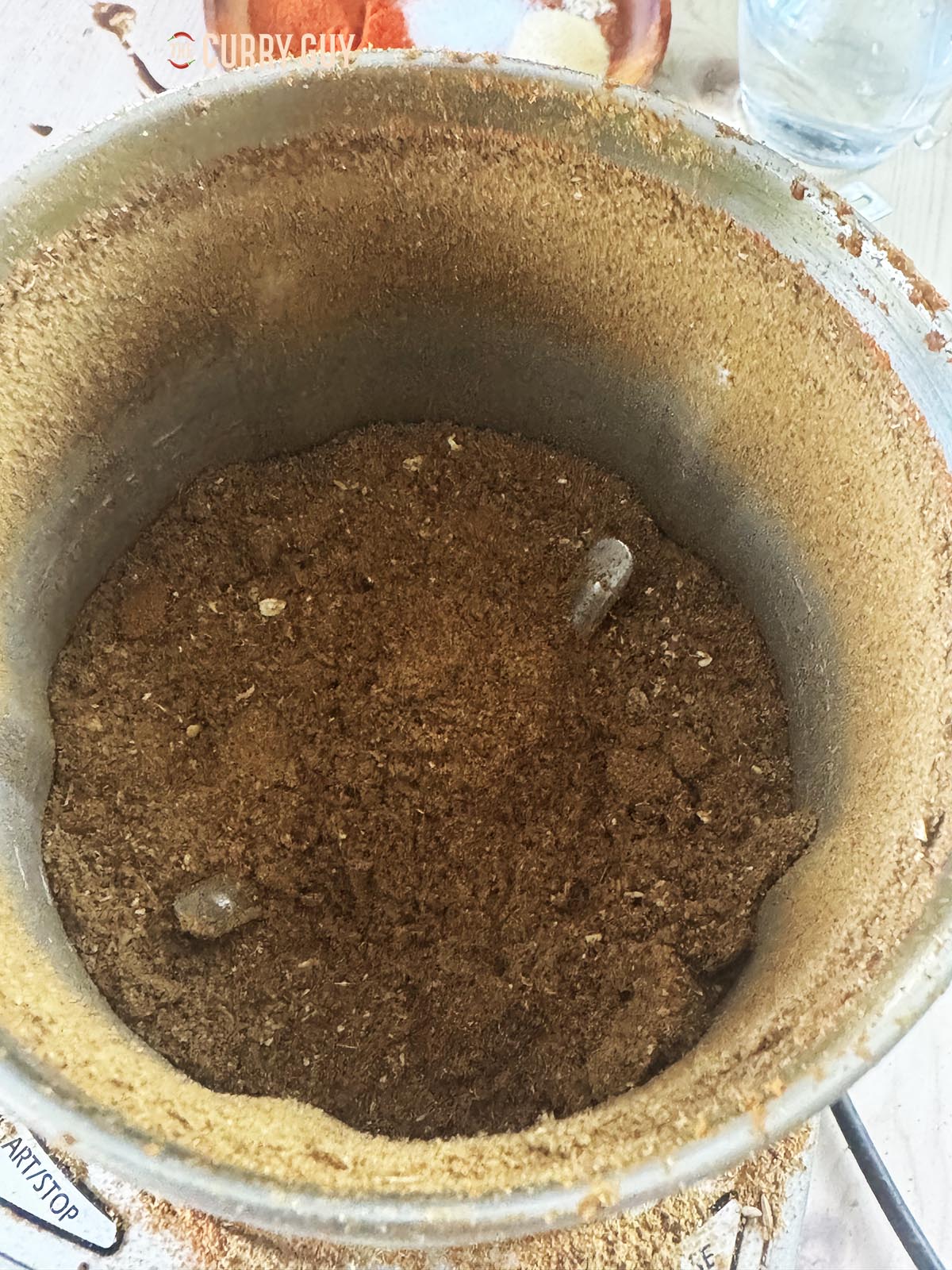 Grinding the whole spices to a powder in a spice grinder. 