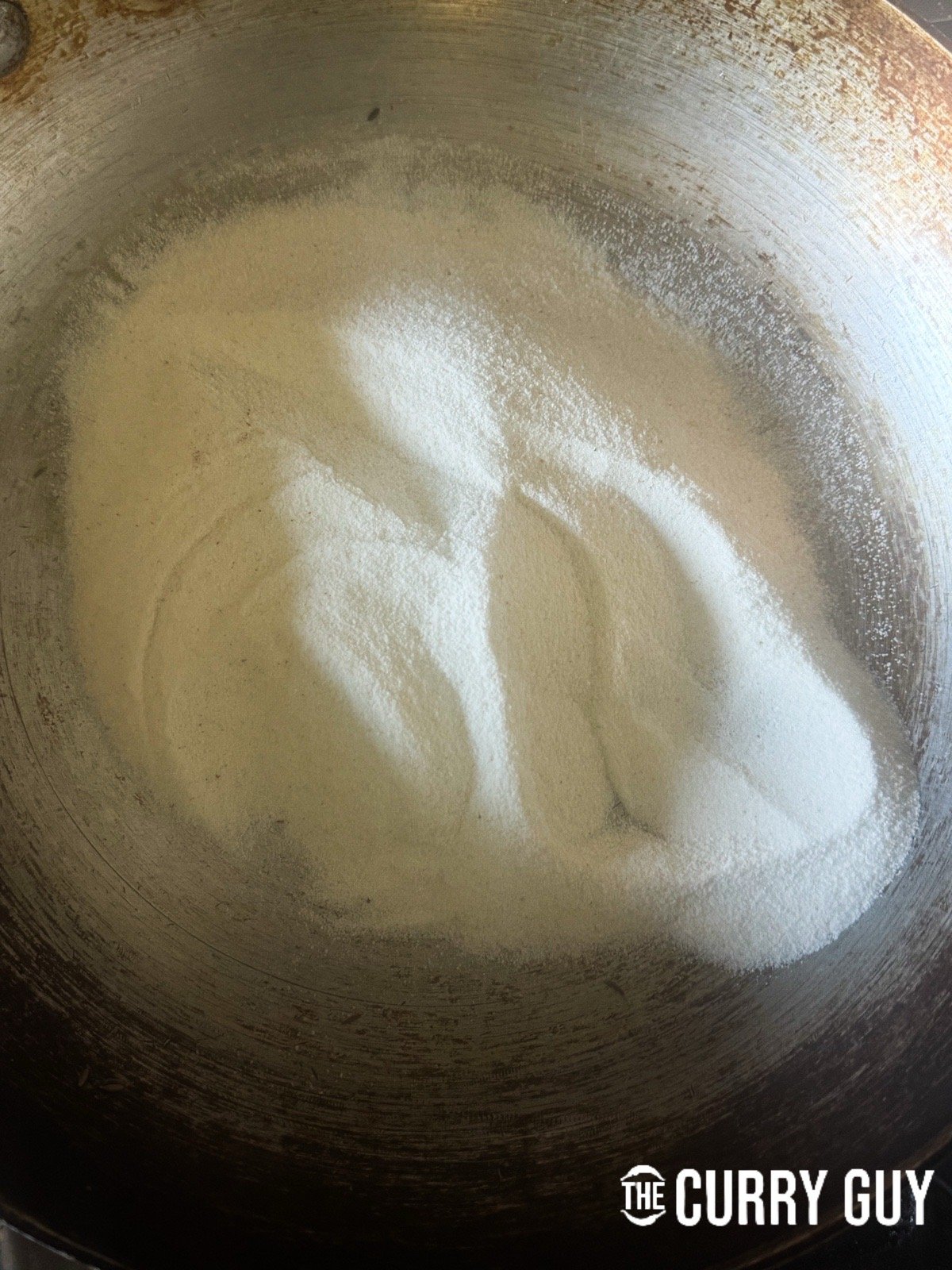 Adding rice flour to a pan to toast it.