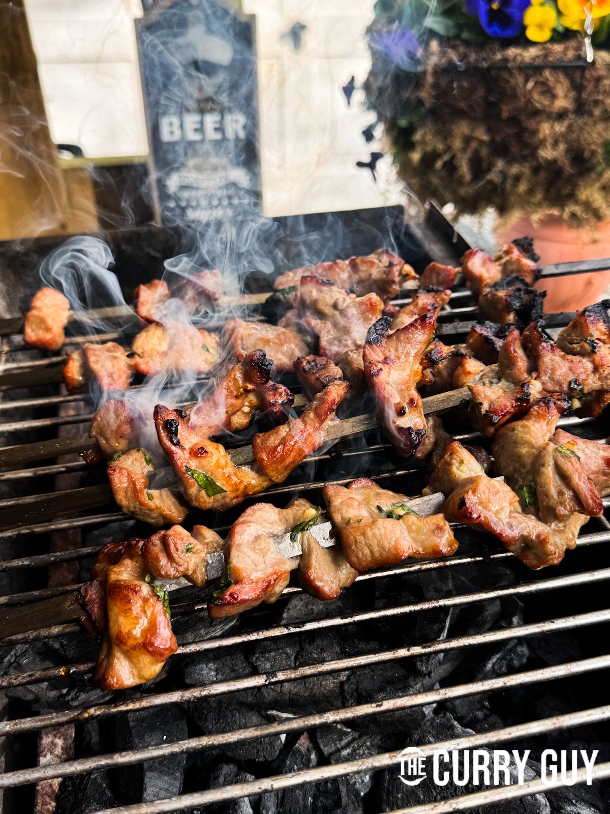 Cooking the Thai pork skewers over hot coals on a barbecue.