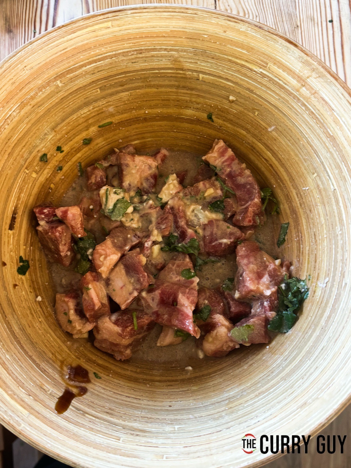 The pork meat in the Thai marinade in a mixing bowl.