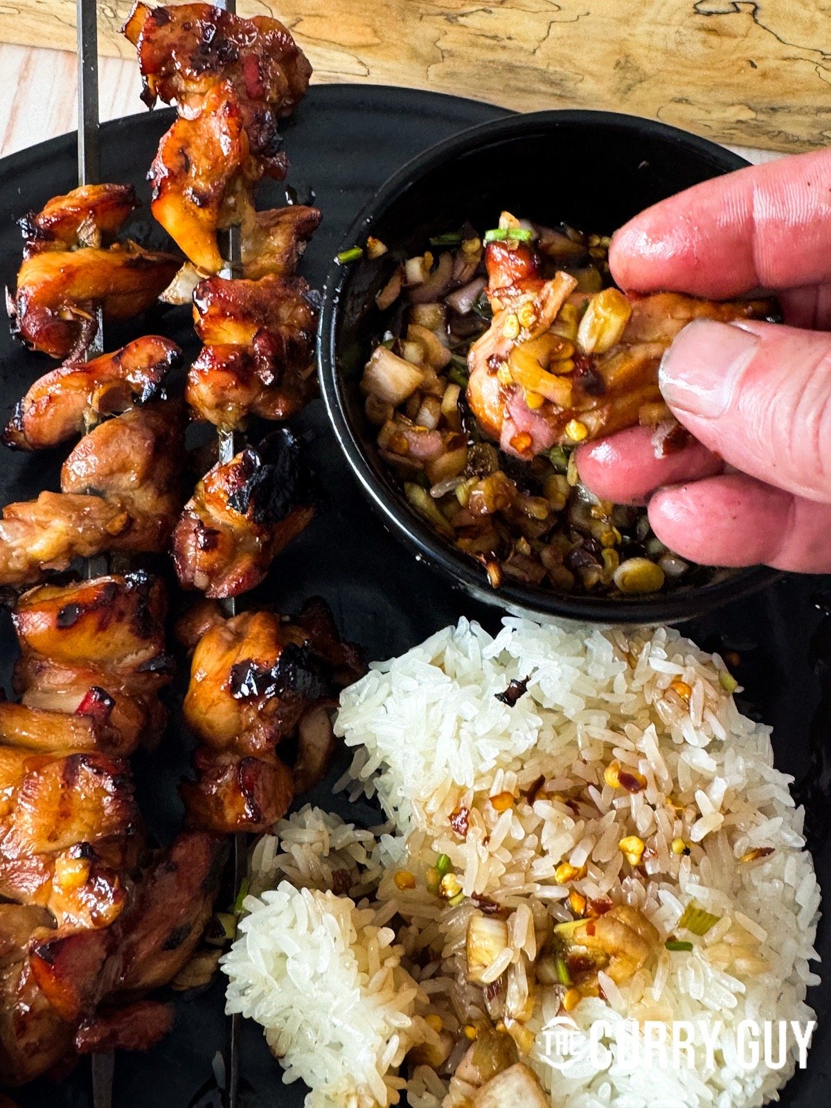 Dipping a piece of chicken into nam jim jaew sauce.